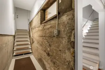 Hallway entering the lower MIL from the south side exterior door- the furnace is at the end of the hall and there is a large crawl space that can fit storage.