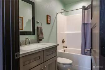 Adjacent to the Guest Bedroom is a one piece tub/shower and again tile floors, wood cabinets & matching hard surface counters
