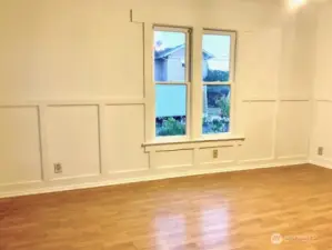 Spacious living room with wainscotting and beautiful sashed windows.