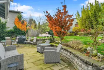 Landscaped back yard with stone patio and rock walls