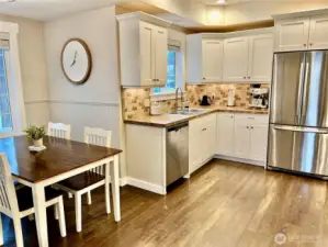 Charming country-style white kitchen cabinets complemented by stainless steel appliances and a stylish tile backsplash, creating a fresh and functional cooking space.