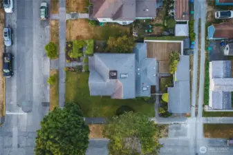 Aerial view showing the entire corner lot with house, garage, shop, fenced backyard and alley access.