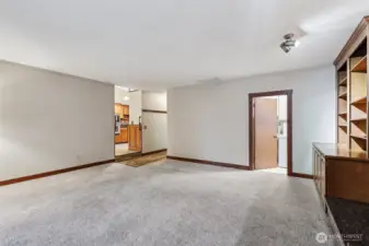 Another view of the family room. The laundry room is adjacent to it. The hallway on the left leads to one of the bathrooms and the garage. The kitchen is located at the back.