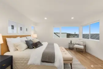 Talk about natural lighting! This spacious primary suite is bathed in natural light, showcasing wrap-around windows that frame stunning neighborhood and skyline views.