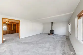 Large living area w/ free standing wood stove & also newer carpeting