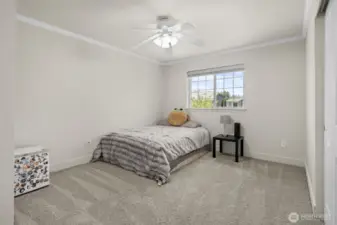 Fourth bedroom with crown molding, ceiling fan, and updated carpet and trim