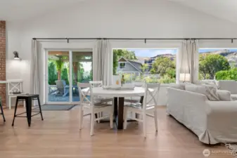 Light-filled great room with modern designer furnishings, neutral tones, and a wall of windows that open the home to surrounding views and sunshine