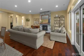 Custom mantle and brick fireplace anchor the great room, complemented by built-in cabinetry, engineered hardwood floors, and French doors with a glass transom that open to the large covered patio.
