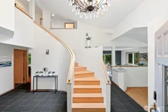 The gorgeous and spacious entry features a grand curving staircase ~ it opens to the step-down formal living room on one side and the family room on the other.