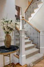 A beautiful staircase featuring a timeless blend of rich wood and wrought iron details creates a classic, elegant focal point in the entry.
