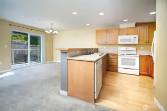 Kitchen with wood floors, bar, dining area with large slider.