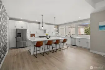 Kitchen features an oversized island, quartz counter tops and gas range.