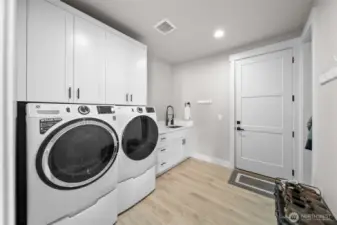 Laundry room off of garage with sink area, storage and coat closet.