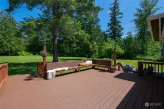 The expansive back deck offers built-in seating with a stunning natural green backdrop, perfect for enjoying a tranquil, rural setting while being close to city conveniences.