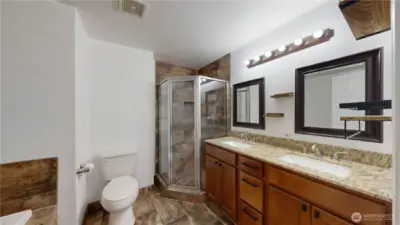 Ensuite primary bath with walk-in closet and a 5-piece bath with soaking tub, tile shower, double vanity, granite counters, and tile floors