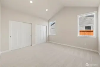 The primary bedroom has a vaulted ceiling and a wall of closets.