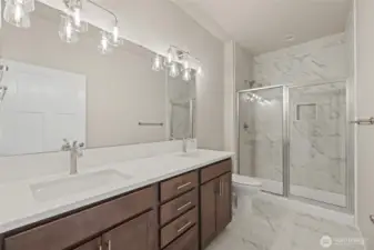 The primary bathroom has two sinks, a tile shower & tile floors.