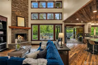 Soaring 2 story stone fireplace in great room, and wall of windows that let in tons of natural light and forest views.  Can you imagine a Christmas tree in front of this window?