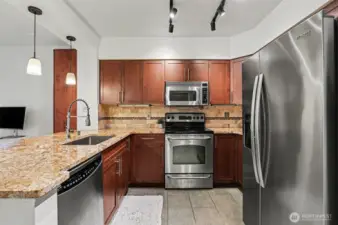 Kitchen features large, slab granite counters and stainless appliances.