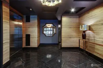 Upscale lobby with designer wallpaper and lighting features. The elevator and stairs to the left and mailroom to the right.