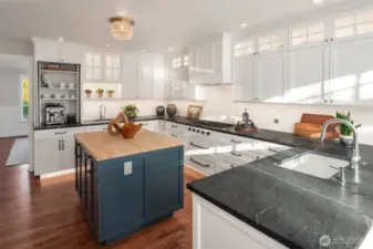 The gourmet kitchen is a chef’s dream, featuring custom cabinetry, rich soapstone countertops, and top-of-the-line appliances from Wolf, Sub-Zero, and Asko. Thoughtful details anticipate every need, with toe kick lighting, double sinks, and touch activated faucet