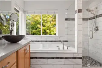 Frameless glass enclosure on this beautifully tiled shower with wall-mount and handheld showers.