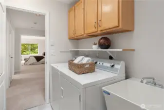 The main floor laundry room features a sink and overhead storage with full size washer and dryer.