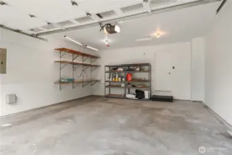 This large 2 car garage has bonus room for shelving and you can see the sprinkler controls to the left. The interior door leads to the laundry room.