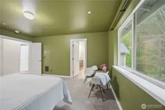 Primary bedroom with large windows looking to the treed backyard