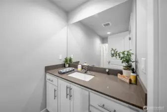 Full bathroom with quartz countertops.