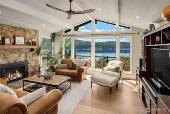 Living room with vaulted ceilings, window wall & gas fireplace. New hardwood floors, doors & trim on the main level & Milgard Windows throughout.
