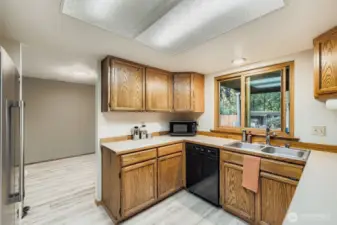 Oak cabinets, stainless steel refrigerator, and a double sink overlooking the spacious back yard.