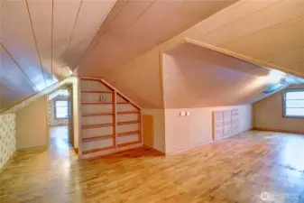 Upstairs bonus room with bookshelves, built-in drawers, hardwood floors and 1/2 bathroom.