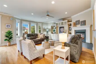 Warm hardwood floors, tall windows, elegant crown molding, built-in features, and a cozy gas fireplace with intricate millwork create a welcoming atmosphere for guests.