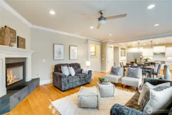 A spacious living area perfect for gathering with guests, featuring tall ceilings, a bright and airy ambiance, that seamlessly opens to the kitchen and an inviting eating nook.