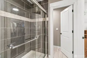 Primary bath features a sleek tile surround with glass doors & decorative tile.