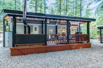 Exterior view of the park model w/ covered deck & pergola lighting.