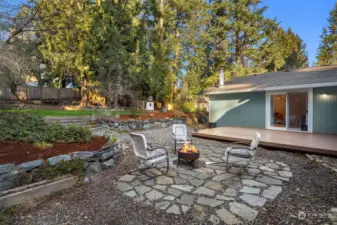 Patio with firepit adjacent to walkout back deck and grass area.