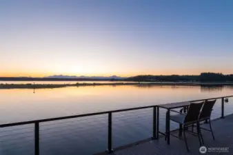 A serene waterfront view at sunset, with the stunning Olympic Mountains in the backdrop.