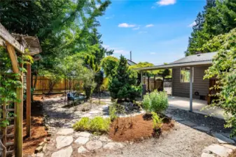 Continuing our tour outside, the backyard is a sweet oasis of entertainment space, mature plantings, and lovely spots to relax.