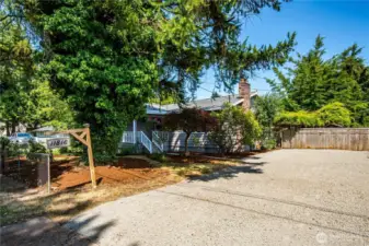 A level, generous driveway holds several cars. It has a new covering of gravel.