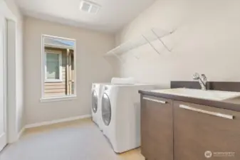 Laundry room on upper level with full size washer & dryer, sink and cabinets.