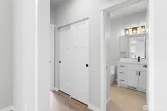 The hallway leading to the lower level bedroom includes a sliding door closet for linens and more.