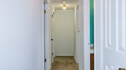 Hallway with 1st door on left as bedroom, 2nd door on left is bonus room that leads to large addition and third bedroom, 1st door on right is full bath with laundry, 2nd door on right is second bedroom.