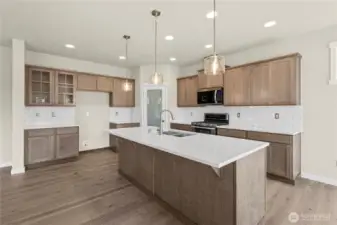 Modern kitchen featuring large center island with sink, quartz counters & eating bar.