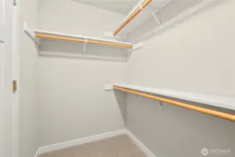 Primary closet is walk-in with extra storage shelves above the hanging rods.