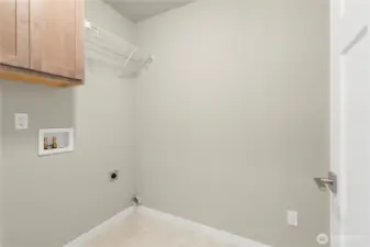 Separate laundry room with a counter, storage cabinets and a storage shelf above appliances.