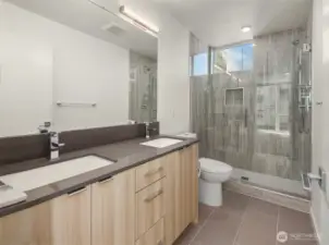 Primary ensuite bathroom with double vanity and floor-to-ceiling tile shower.