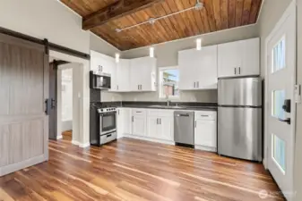 Full kitchen has compact size appliances to maximize counter space. Through the barn door at left is a private BR with full en suite bath.