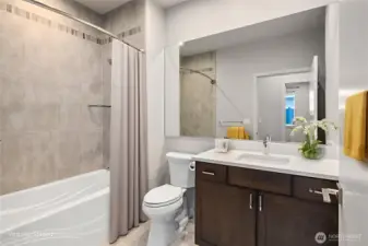 The combination of a spacious shower/tub and tasteful tilework enhances the bathroom’s appeal, making it a comfortable and inviting space.